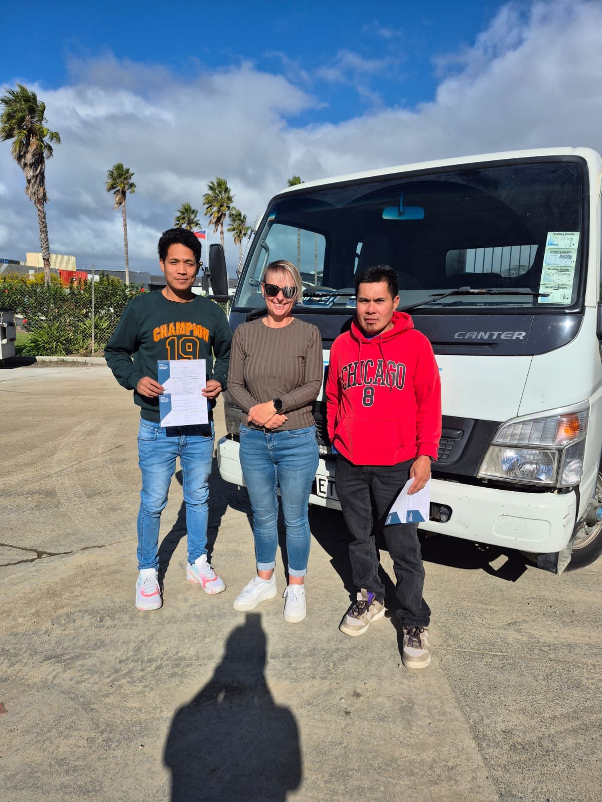 2 recent graduates stand by instructor and truck