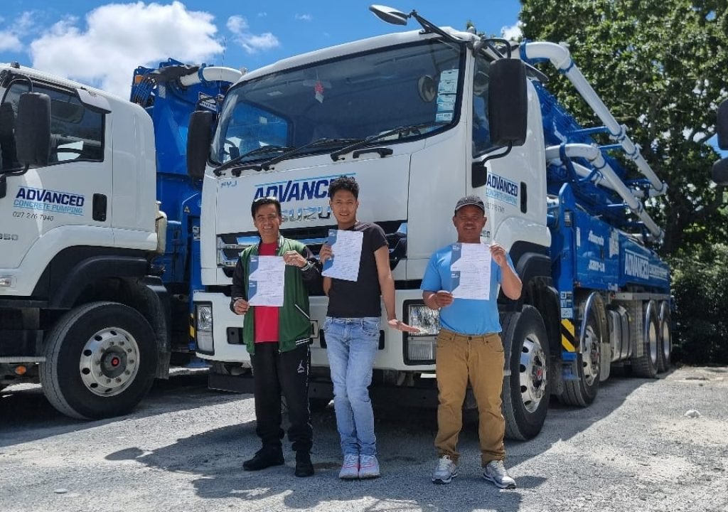 3 Students stand in front of training vehicle